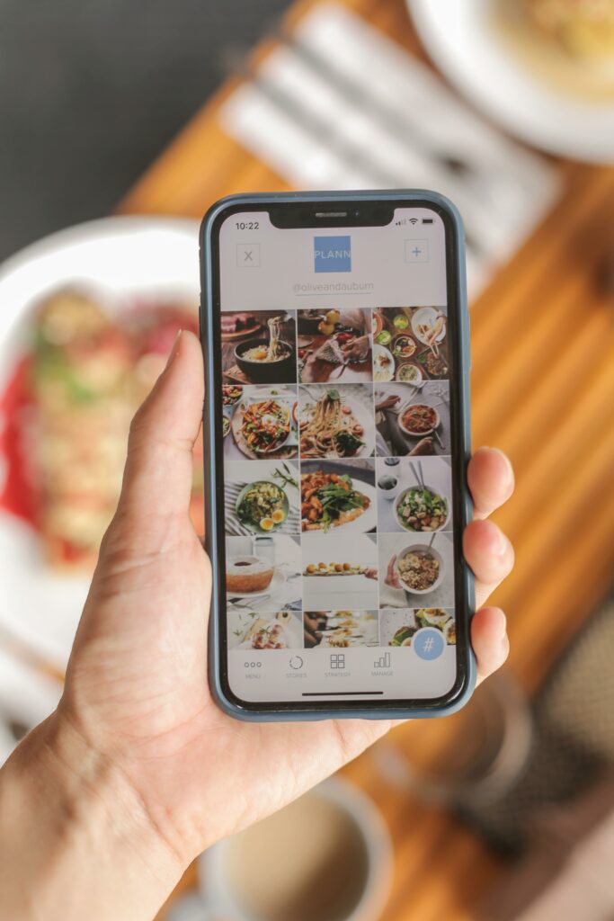 pexels photo 4565778 4565778 A hand holding a smartphone displaying a food app interface, showcasing diverse dishes.